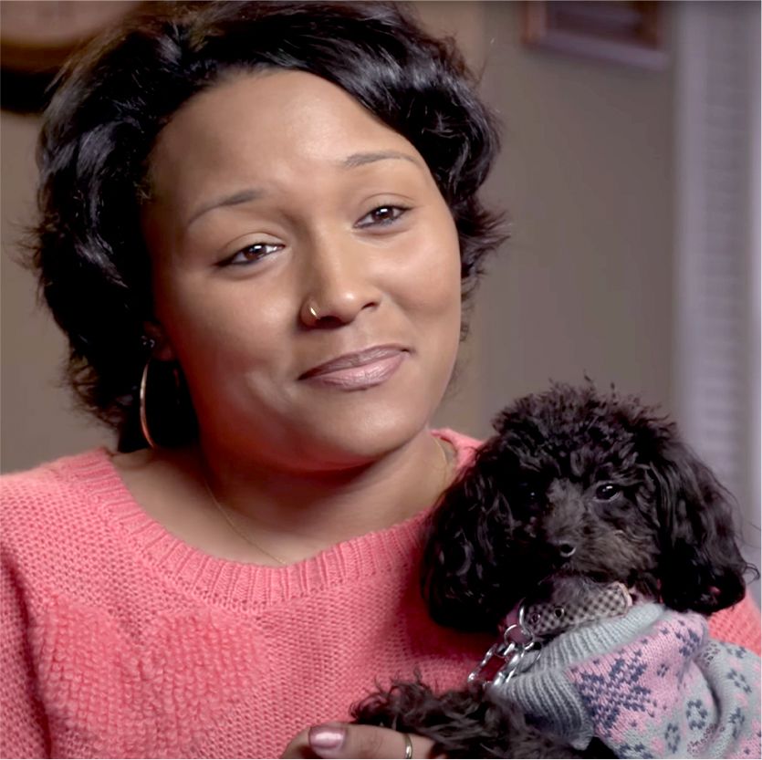 Photo of Shawneeqa and her small black poodle in their home